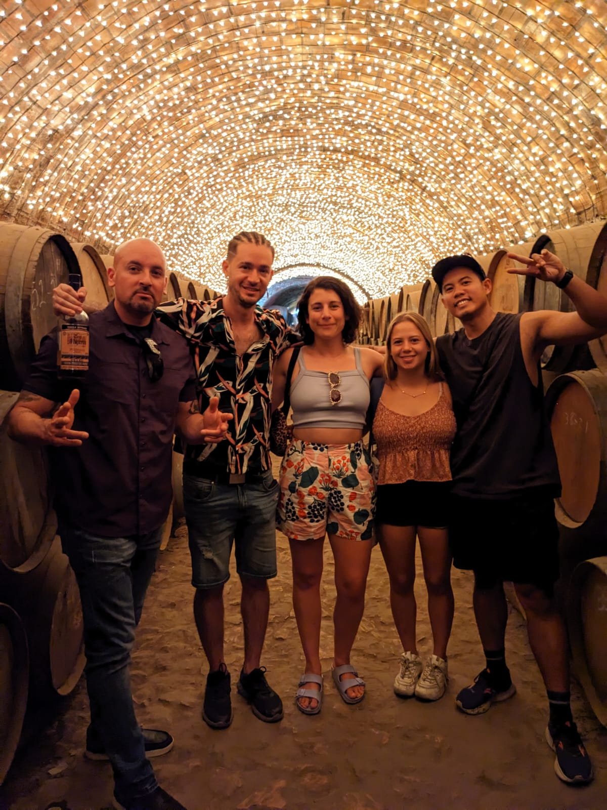 Grupo en bodega iluminada con barriles de vino.