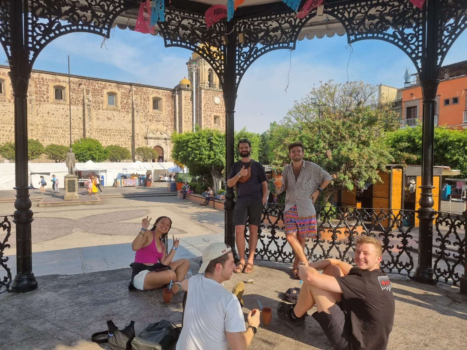 Amigos relajándose en quiosco de plaza mexicana.