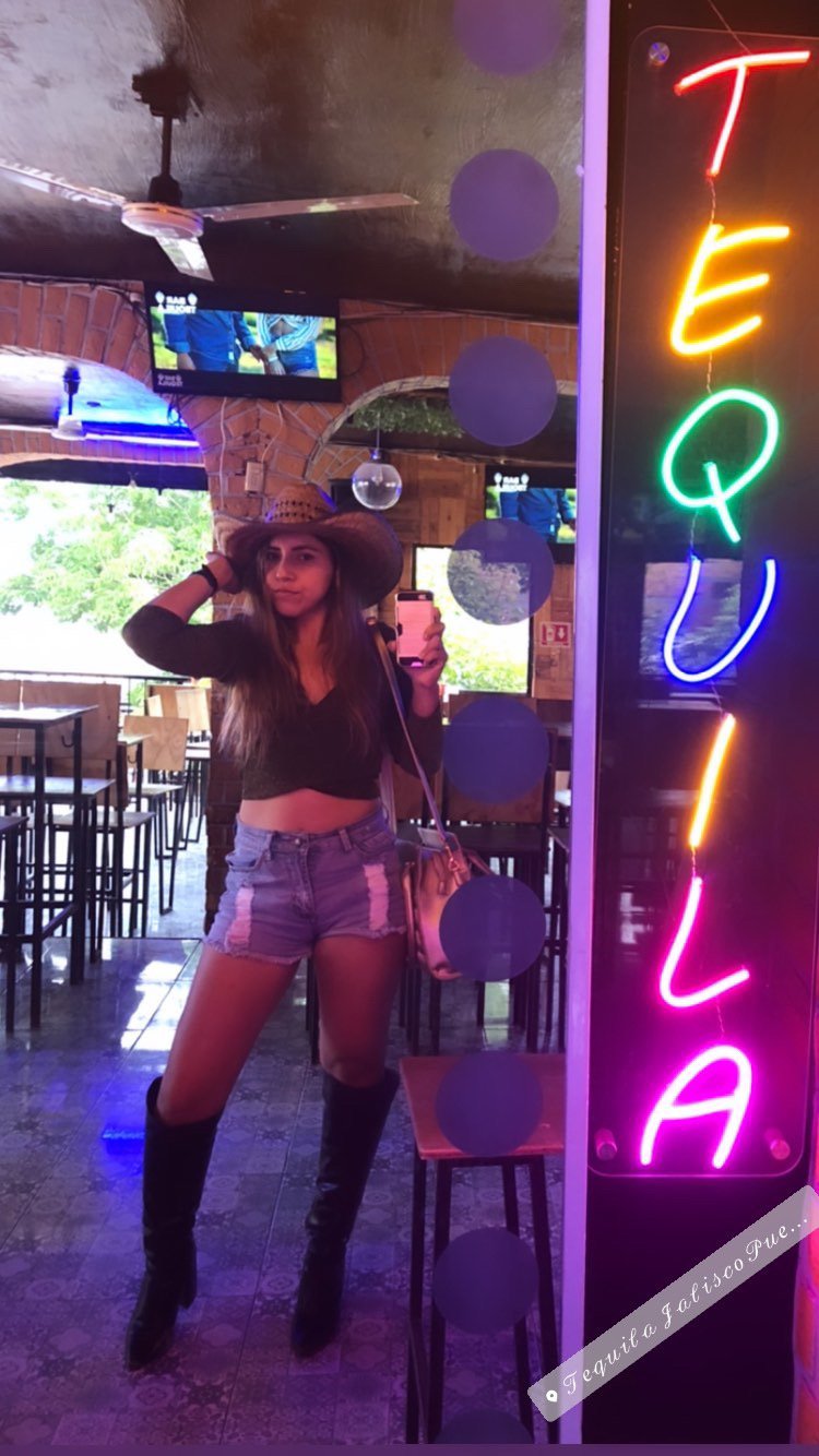 Mujer joven en bar con letrero de tequila.