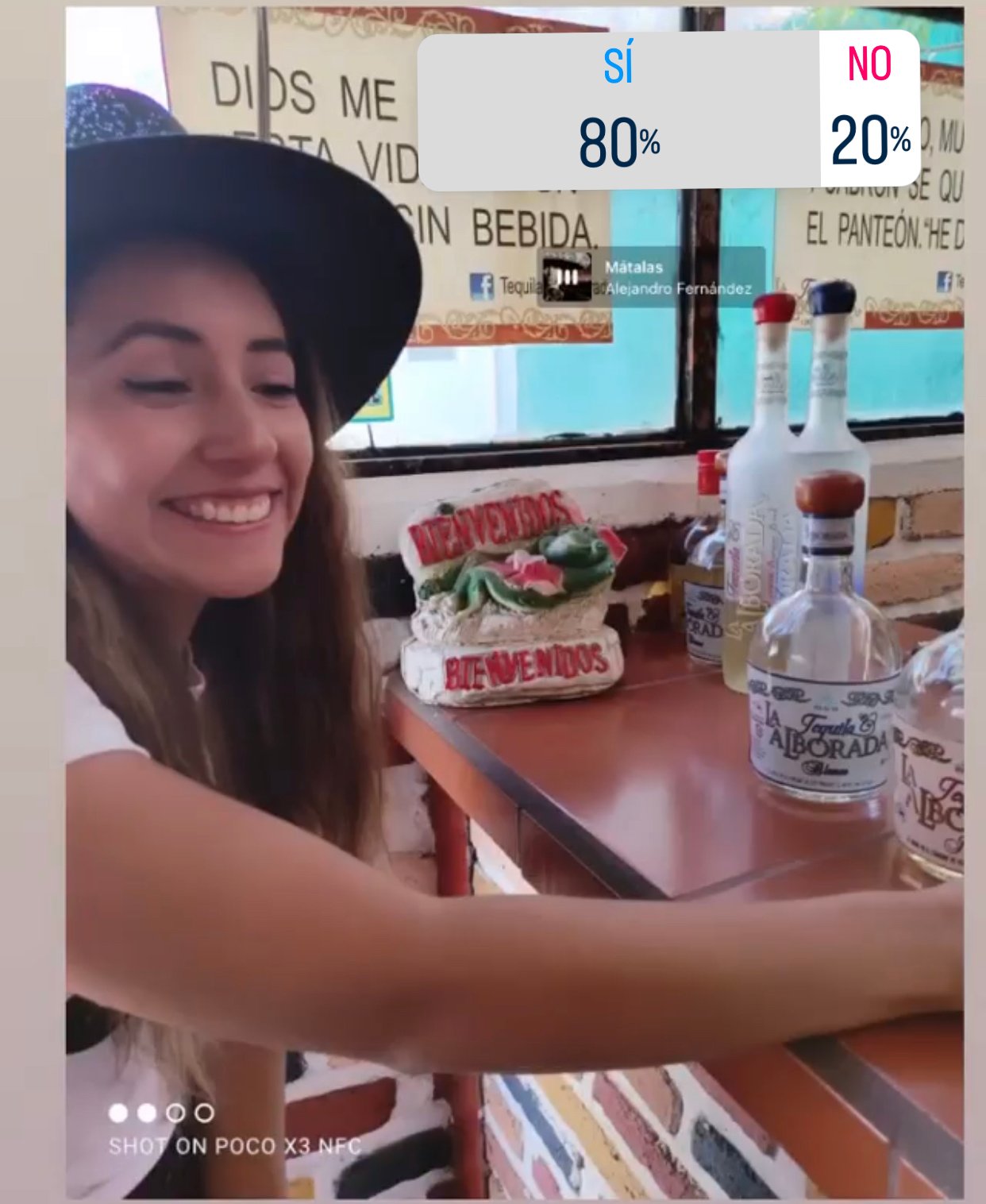 Mujer sonriente con sombrero en tienda de tequila.