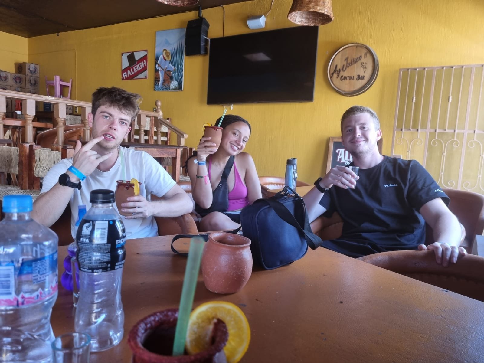 Tres amigos disfrutando bebidas en un bar mexicano.