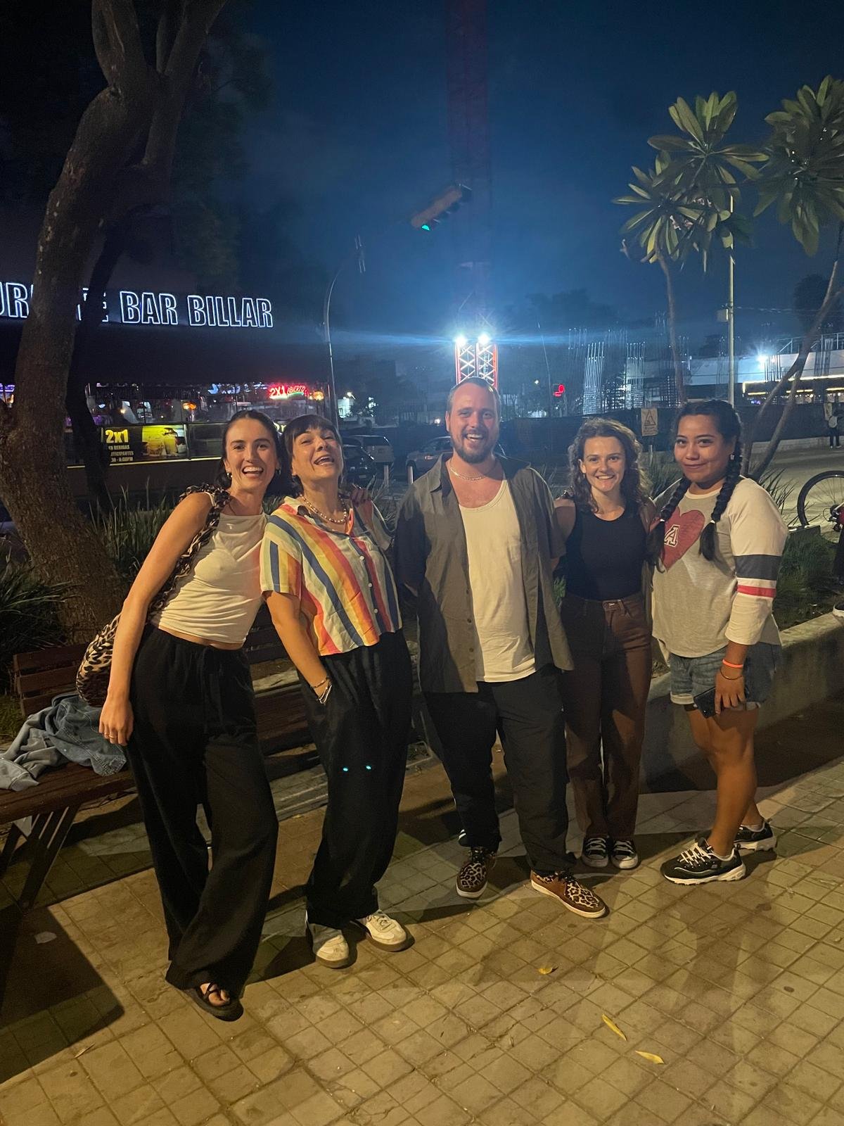 Grupo de amigos frente a un bar por la noche.