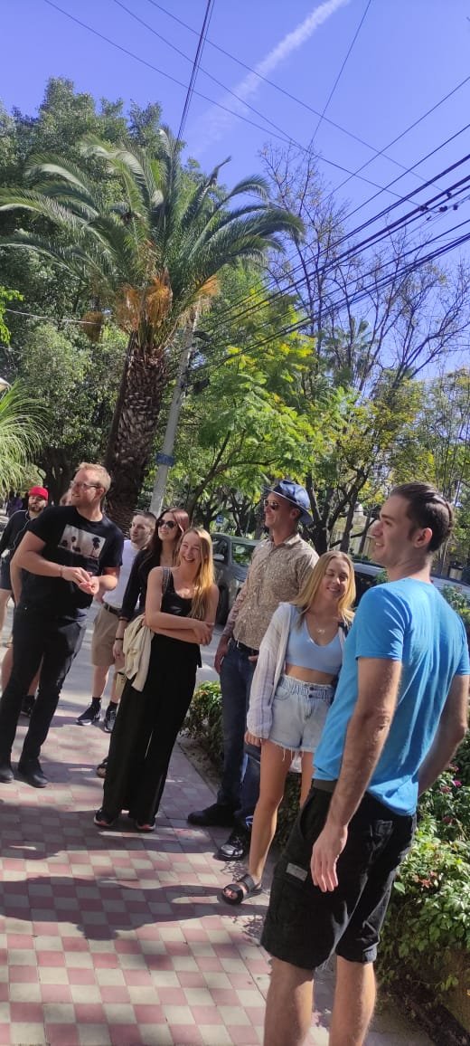 Grupo de personas caminando en una acera soleada.