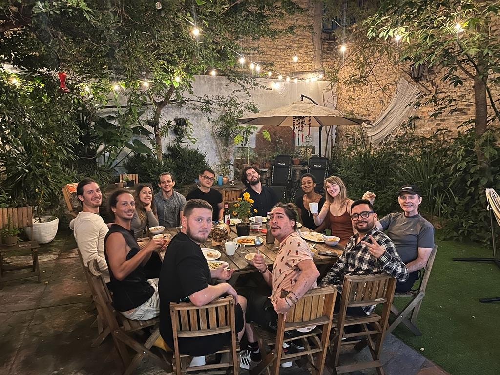 Grupo de amigos cenando al aire libre en jardín.