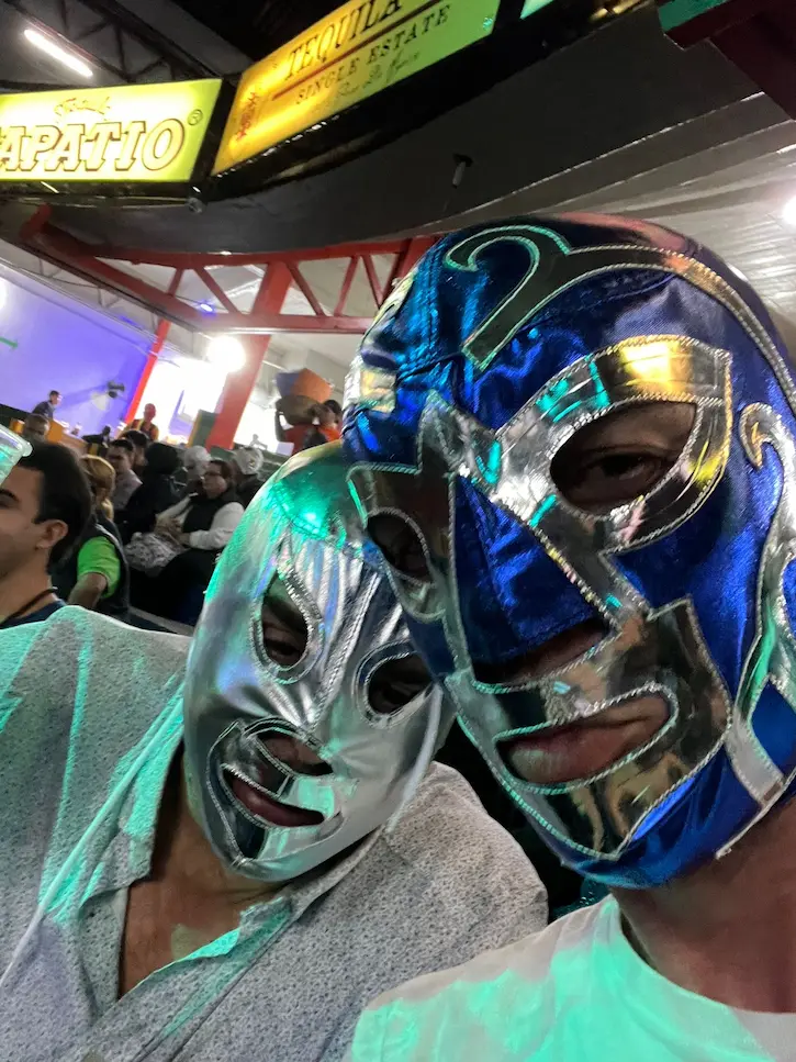 Dos personas con máscaras de lucha libre en evento.