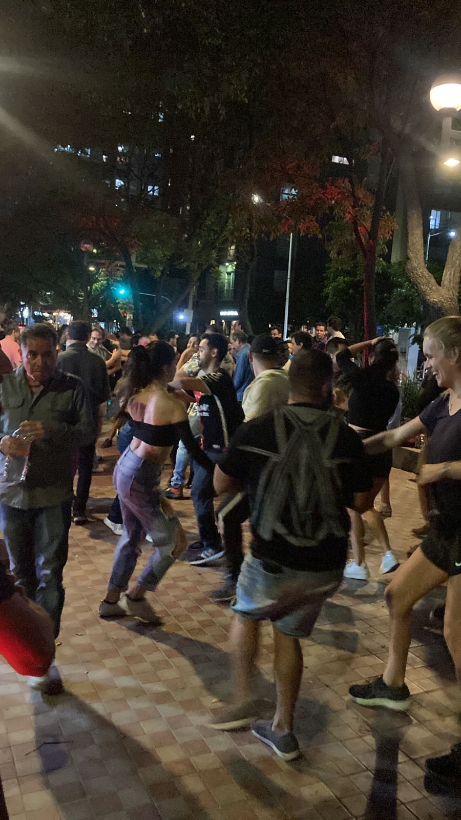 Personas bailando salsa en una plaza.