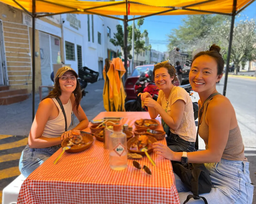Personas comiendo en un puesto de tacos al aire libre.