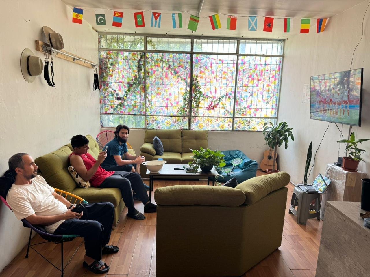 Sala con personas, plantas y banderas decorativas.