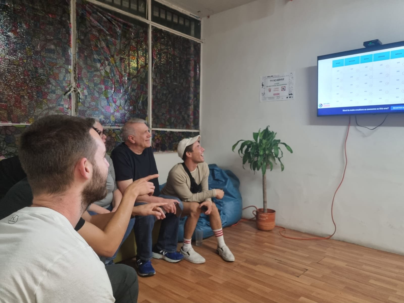 Personas viendo televisión y señalando pantalla.