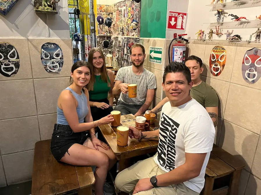 Grupo disfrutando cervezas en bar temático de luchadores.