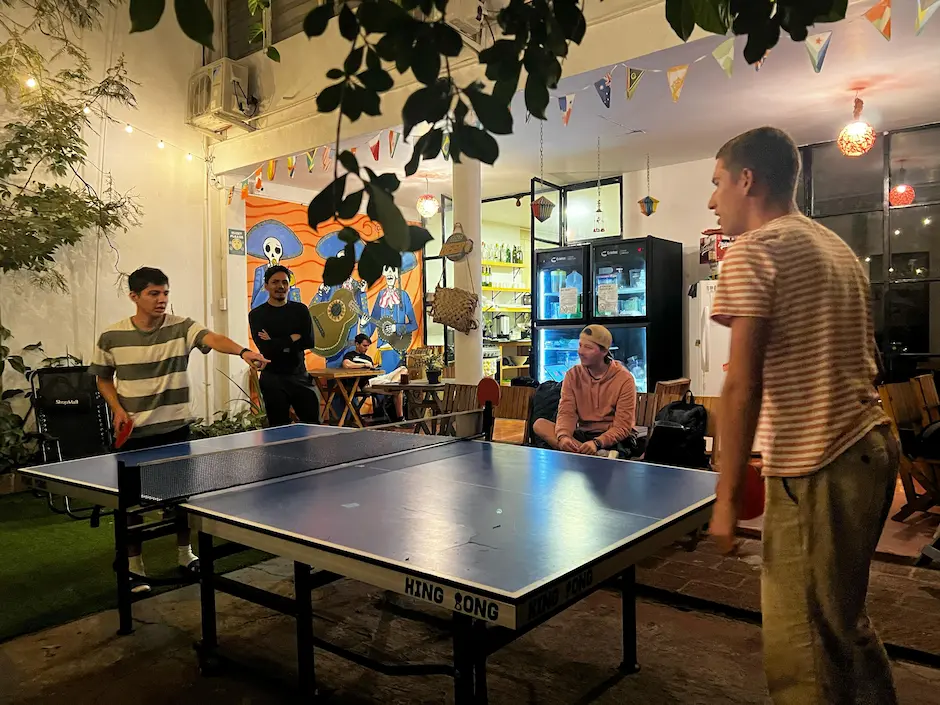 Jóvenes jugando ping-pong en un café decorado.