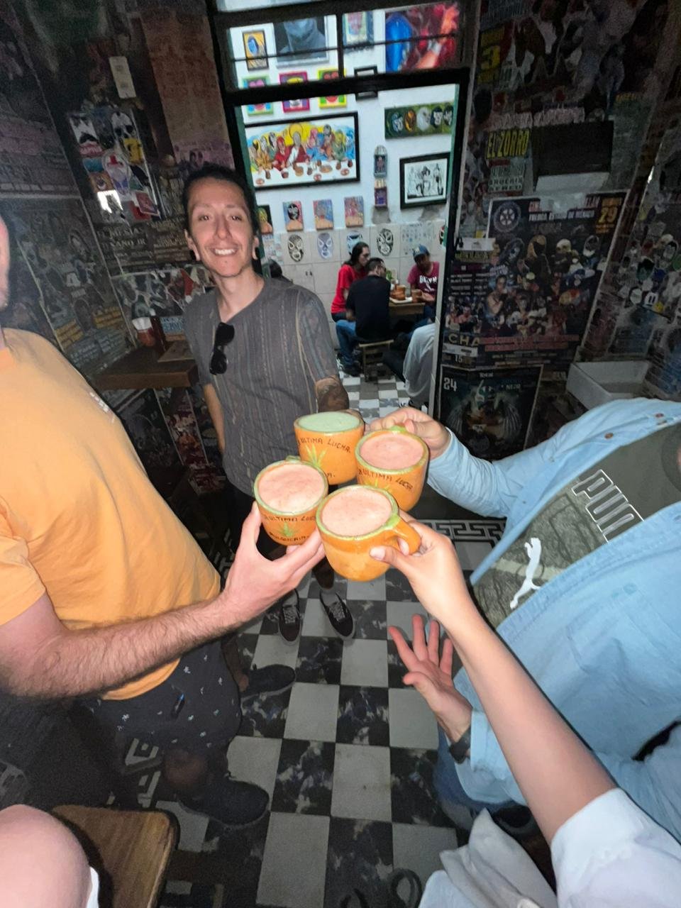 Personas brindando con vasos de cerveza en un bar.