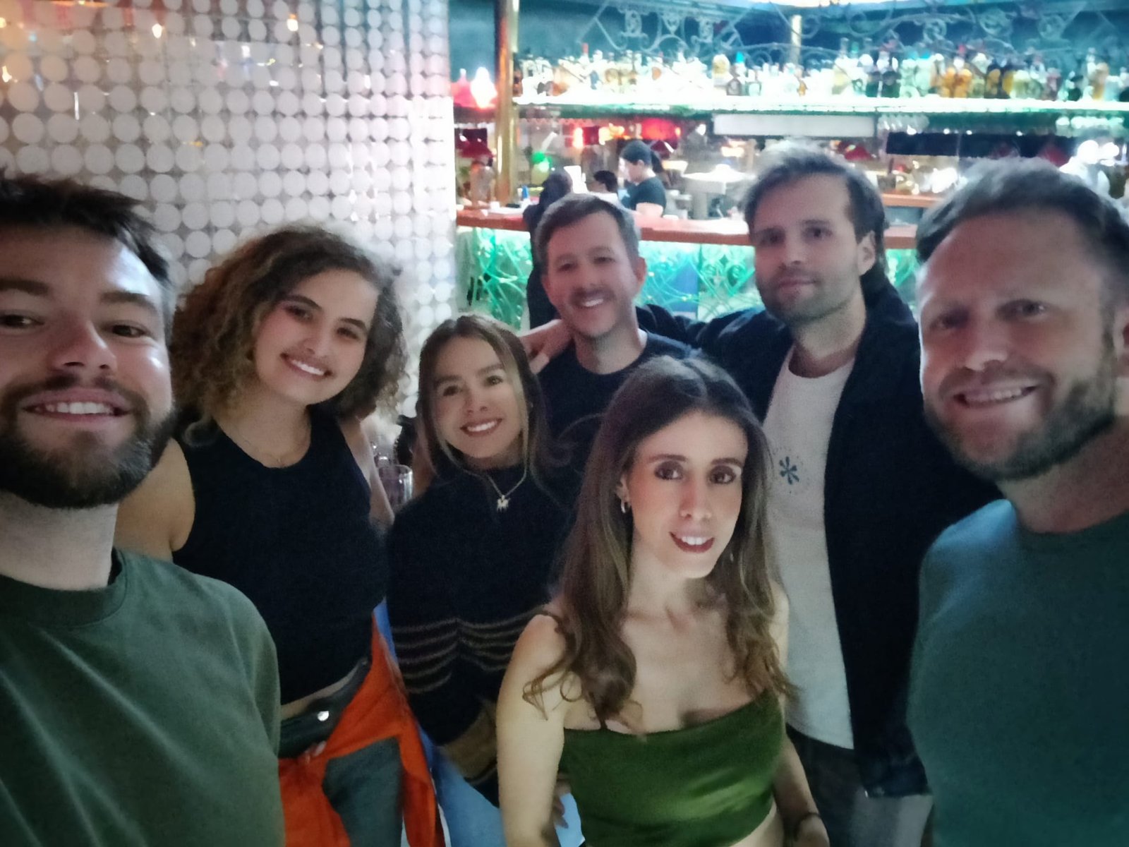 Grupo de amigos sonríen en un bar iluminado.